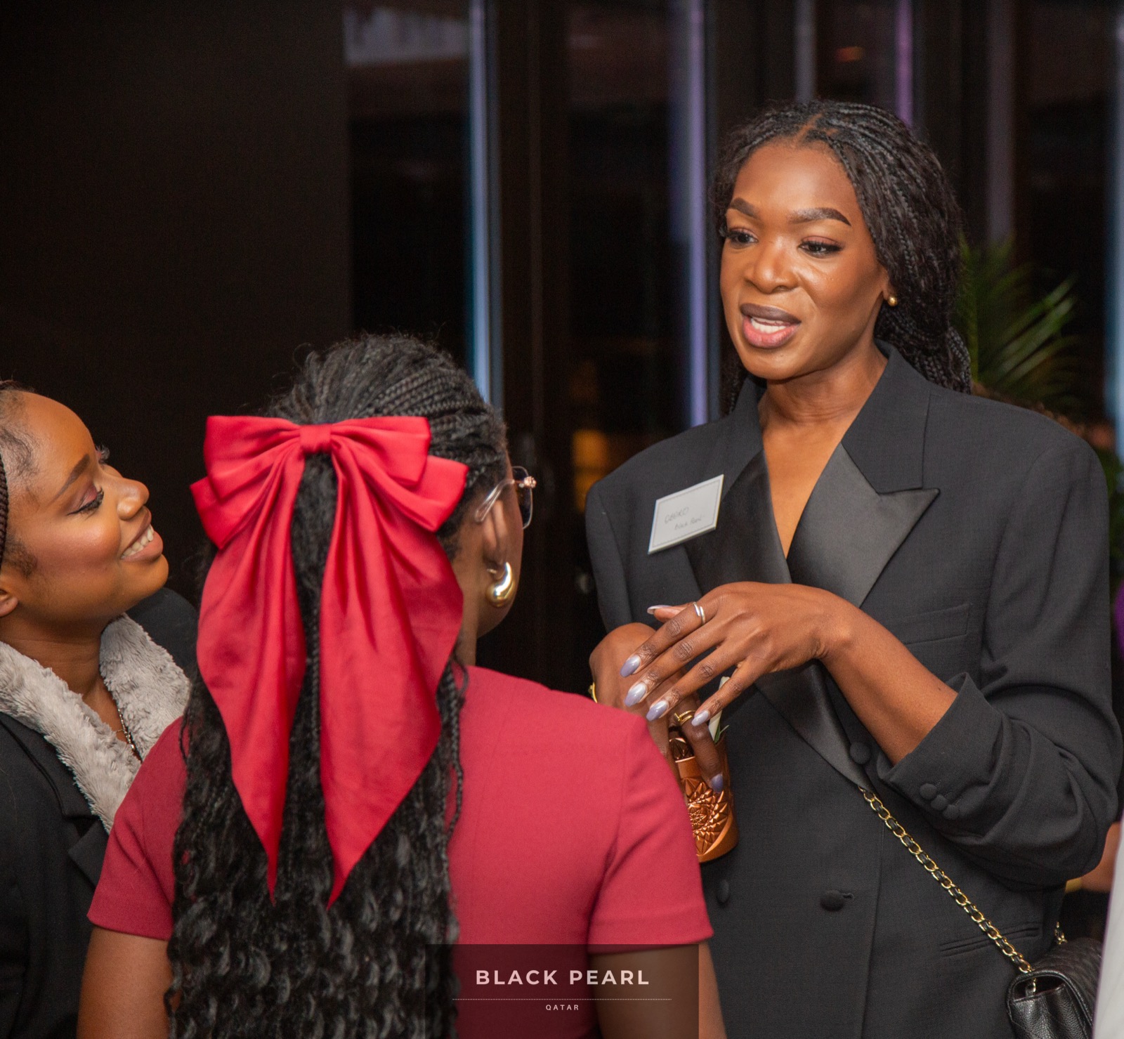 Three women in warm, animated conversation at a Black Pearl evening